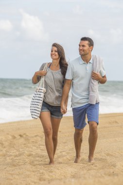 Genç bir çift sahilde yürüyor.