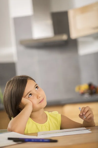 Портрет маленької дівчинки, що робить домашнє завдання ar стіл — стокове фото