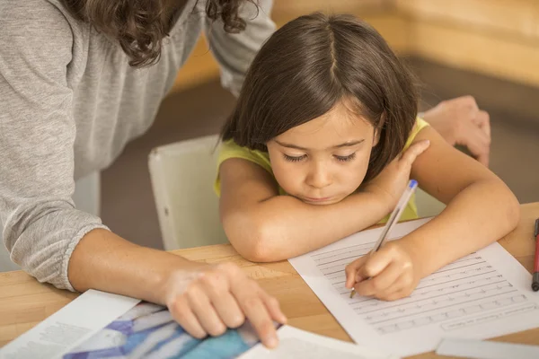 Moeder en dochter samen huiswerk maken. — Stockfoto