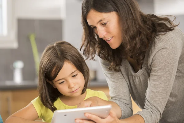 Madre e hija haciendo la tarea con una tableta —  Fotos de Stock