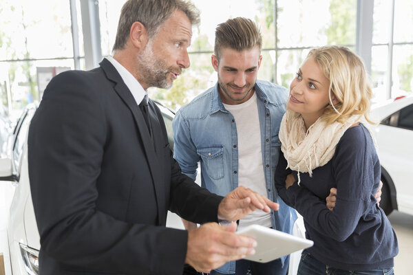 Car dealer showing vehicle binnacle to clients