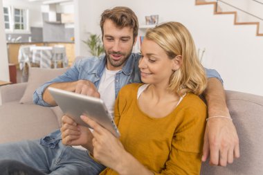 Evde dijital tablet kullanan genç çift