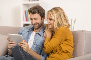 Evde dijital tablet kullanan genç çift