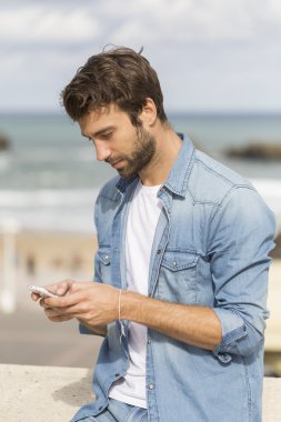 Genç adam akıllı telefon kullanıyor. 