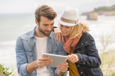 Sahil kasabasında dijital tablet kullanan genç çift