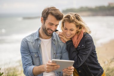 Sahil kasabasında dijital tablet kullanan genç çift