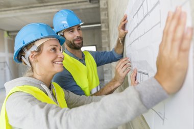 Engineers on building site checking plans clipart