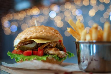 Tahta bir masada peynirli ve kızarmış patatesli hamburger. Bokeh