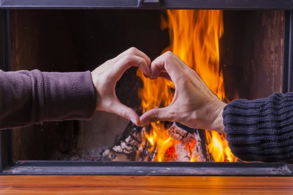 Mannelijke en vrouwelijke hand vormen hart bij open haard — Stockfoto