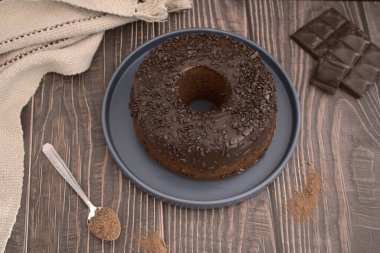 Üst Manzara. Ahşap arka planda ev yapımı çikolatalı kek, yanında da çikolata parçaları.