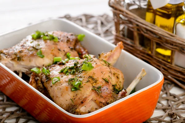 Oven baked rabbit with herbs  on wooden table.