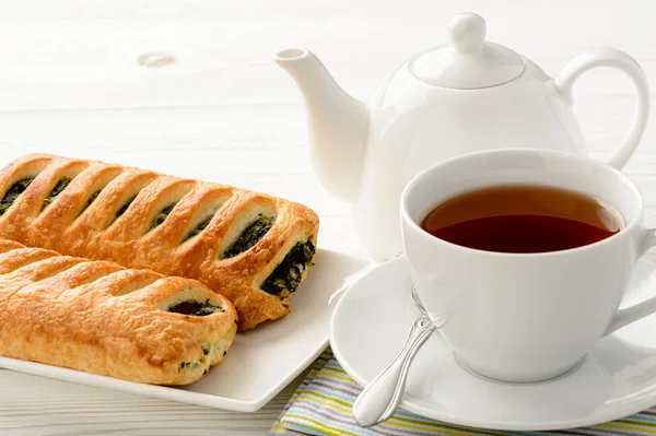 Puff pastry with spinach and cup of tea on the wooden background. — Stock Photo, Image