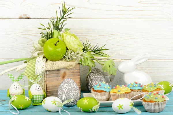 Easter decoration - colored eggs, muffins and bunny on wooden background. — Stock Photo, Image