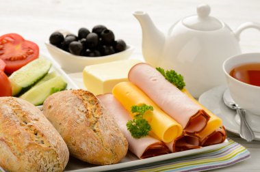 Peynir, jambon, taze çörek, taze sebze, zeytin ve çay ile sağlıklı kahvaltı.