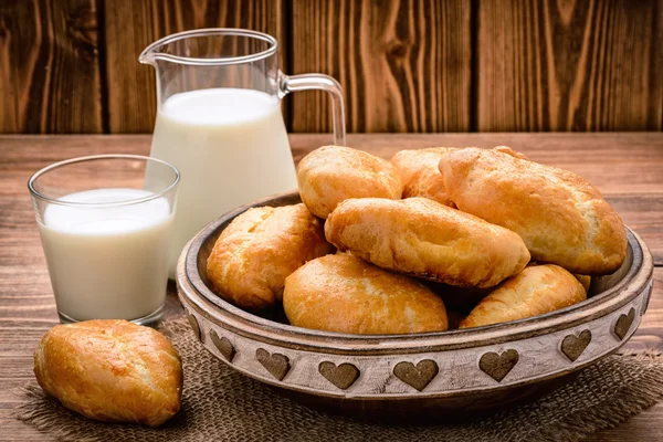 Traditionelles russisches Gebäck Piroshki und Milch auf Holztisch. — Stockfoto