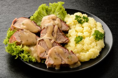 Mantar sos ve patates püresi siyah plaka üzerinde pişmiş bonfile.