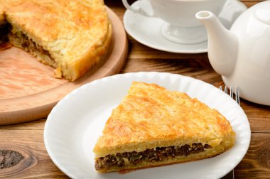 Ahşap masa kıyılmış etli turta.