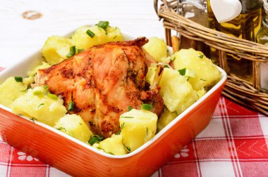 Beyaz ahşap masa üzerinde turuncu seramik kase patates ile tavşan fırında fırın.