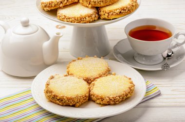 Tereyağlı kurabiye (alfajores) karamel ve fıstık ve ahşap arka plan üzerinde çay ile.