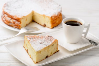 Peynirli kek dilimi ve ahşap zemin üzerine kahve.