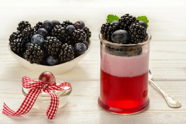 Mousse de gelatina de bayas con moras y arándanos sobre fondo de madera blanca . — Foto de Stock