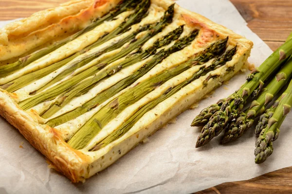 Ahşap masa üzerinde yeşil kuşkonmaz ile tart.