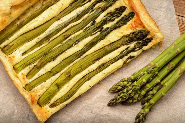 Ahşap masa üzerinde yeşil kuşkonmaz ile tart.