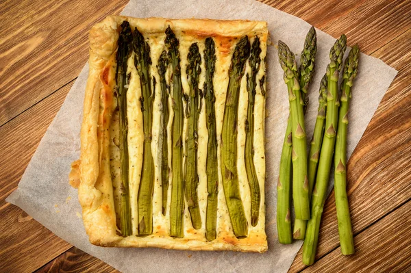 Ahşap masa üzerinde yeşil kuşkonmaz ile tart.