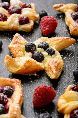 Ahududu, yaban mersini ve siyah arka plan üzerine krem peynir ile puf hamur işleri.