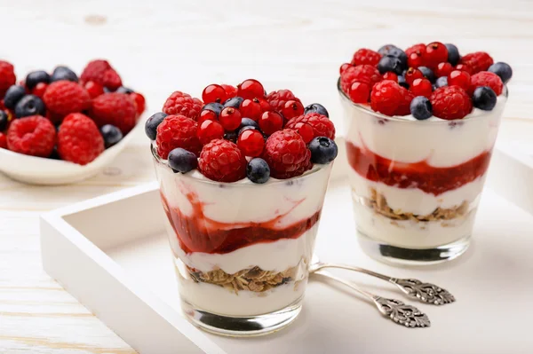 Gesundes Joghurt-Dessert mit Müsli, Erdbeermousse, Himbeeren, Blaubeeren und roten Johannisbeeren. — Stockfoto