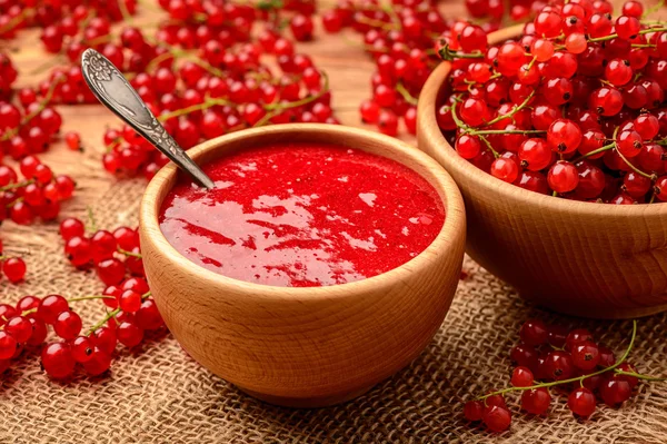 Red currants jam in wooden bowl.