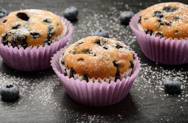 Siyah arka plan üzerine bir yaban mersini ve Blueberry muffins.