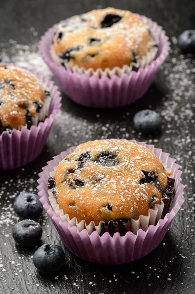 Blaubeer-Muffins und Blaubeeren auf schwarzem Hintergrund. — Stockfoto