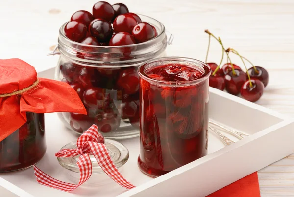 Confiture de cerises dans des pots en verre sur fond en bois . — Photo