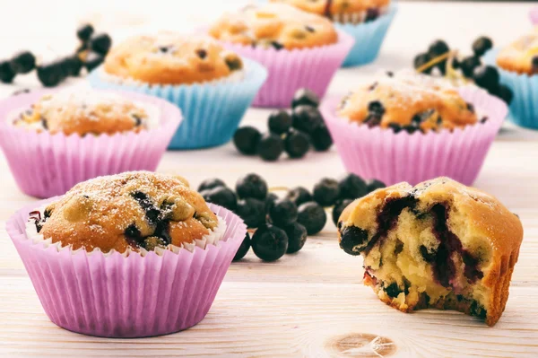 Sweet muffins with chokeberries (aronia) on white wooden table. — Stock Photo, Image