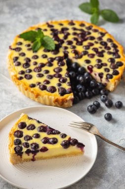Homemade blueberry custard tart on light background.
