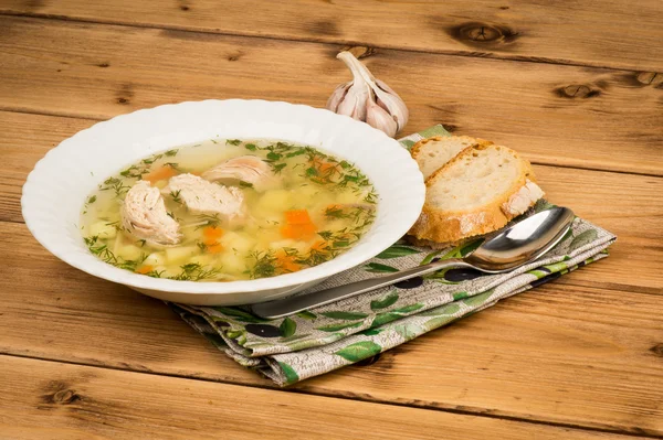 Sopa de frango com pão e alho no fundo de madeira . — Fotografia de Stock