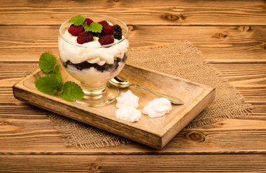 Eton mess - traditional english dessert with cream, berries and meringues on the wooden background. clipart