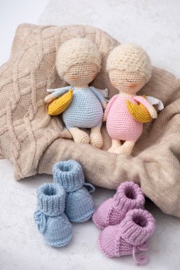 Üç sevimli uyuyan melek bebeği, küçük bir sallanan at ve pastel renkli bebek patik örgü ören el yapımı bebek oyuncakları seti. Amigurumi melekleri yumuşak mavi giyinmişler.