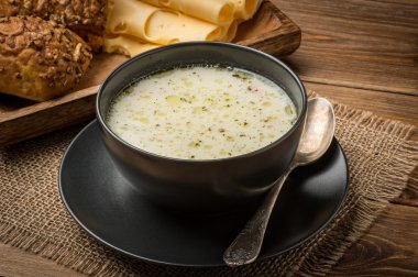 Rustik ahşap arka plan üzerinde siyah bir tabak içinde peynir çorbası.