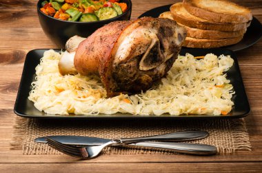 Ahşap arka plan üzerinde lahana turşusu ile servis kavrulmuş domuz knuckle.