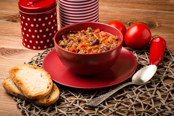 Şili con carne ahşap arka plan üzerinde kırmızı kasede servis.