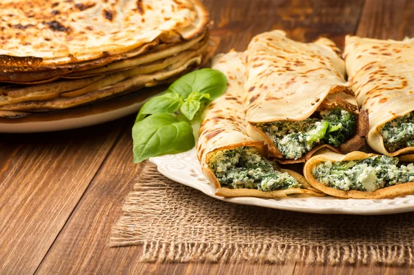 Panqueques rellenos de espinacas y queso en la superficie de madera . — Foto de Stock