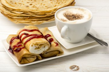 Süzme peynir ve ahşap zemin üzerine kahve dolu krep.