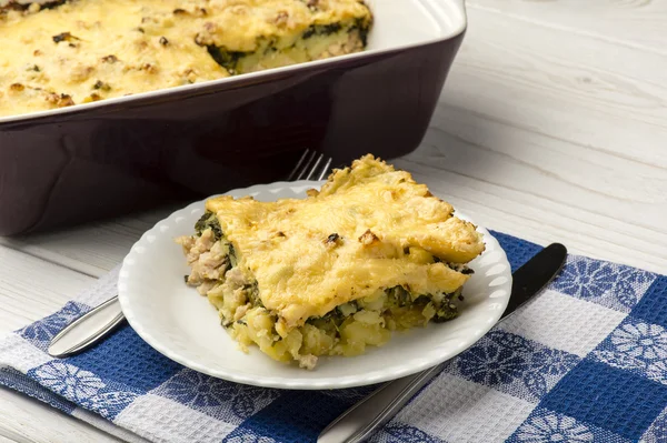 Porzione di casseruola con spinaci, pollo e patate sullo sfondo di legno . — Foto Stock