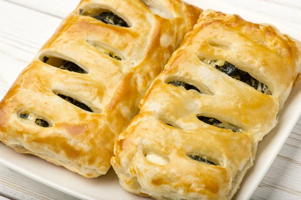 Pastel de hojaldre con espinacas y feta sobre fondo de madera . — Foto de Stock