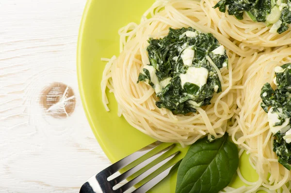 Olasz tészta spenóttal és feta zöld lemez a fából készült háttér. — Stock Fotó