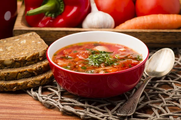 Borscht - traditionelle russische und ukrainische Rote-Bete-Suppe in roter Schüssel auf Holzgrund. — Stockfoto