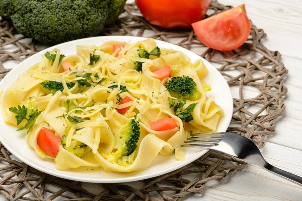 Pasta italiana con broccoli, pomodori e formaggio sul tavolo di legno . — Foto Stock