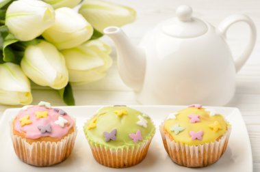 Muffin krema şeker ahşap masa üzerinde beyaz tabak, Lale ve çay pot ile kaplı